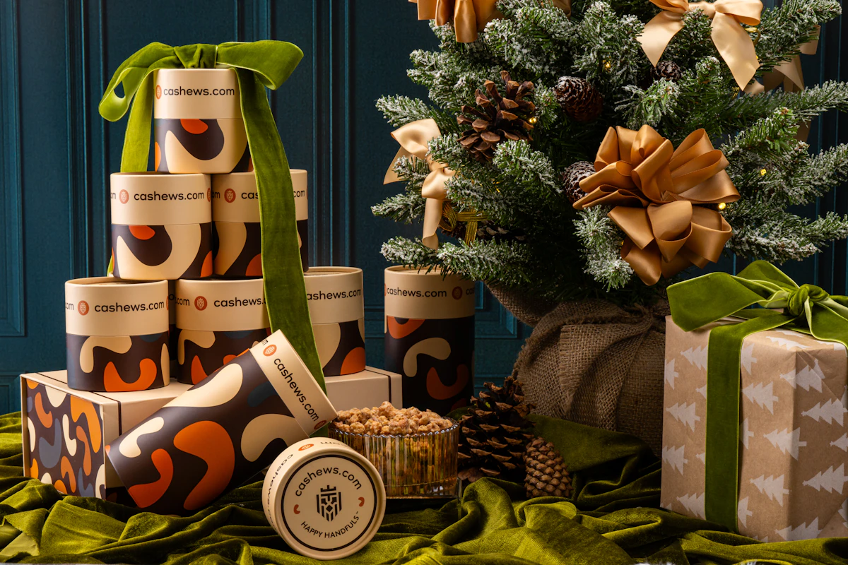 Festive arrangement with gift boxes, cashew containers, and a decorated evergreen tree.