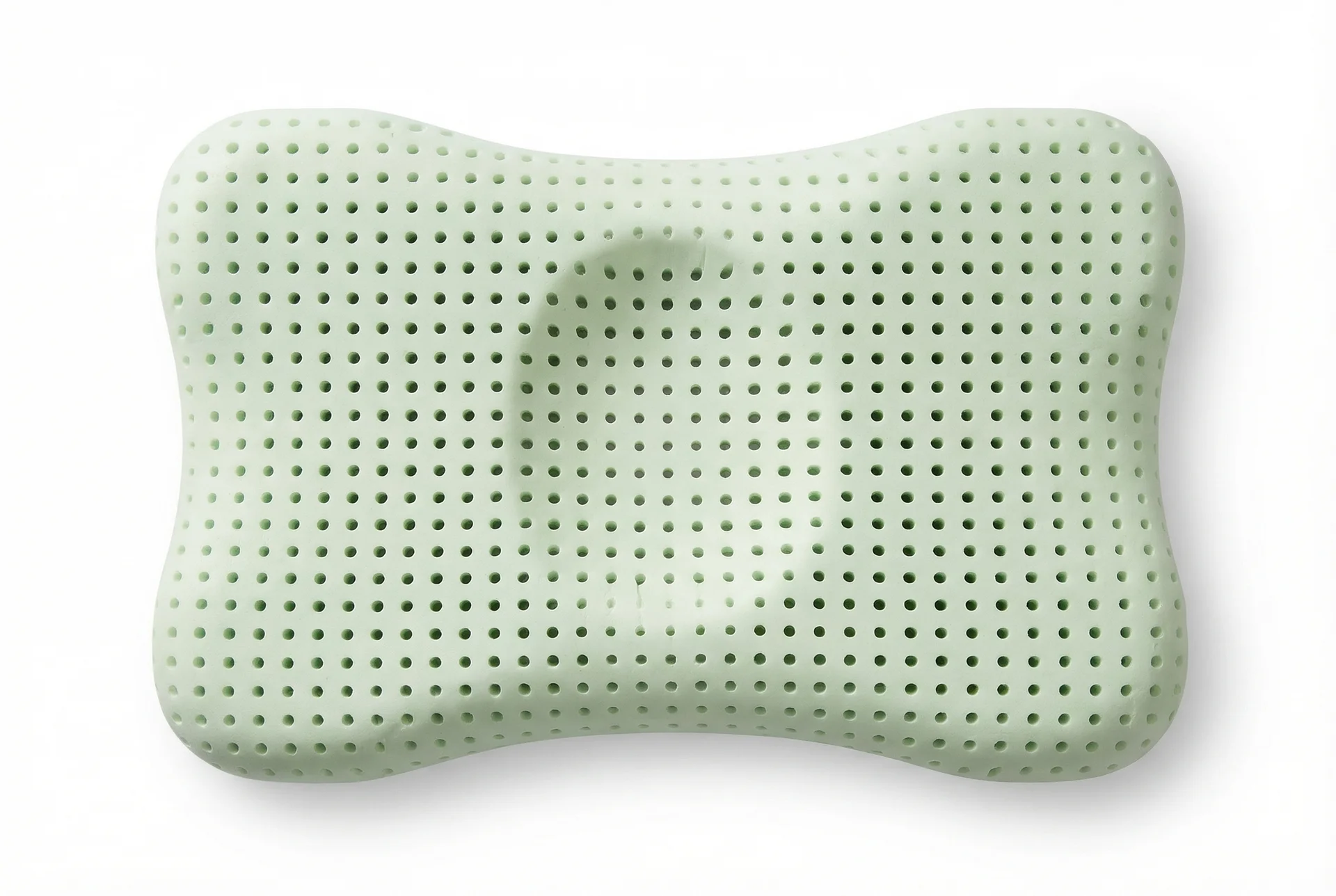 A light green, bone-shaped, perforated pillow on a white background, shot from above.