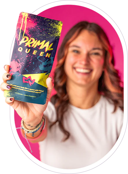 Person holding colorful product labeled 'Primal Queen' against pink background.