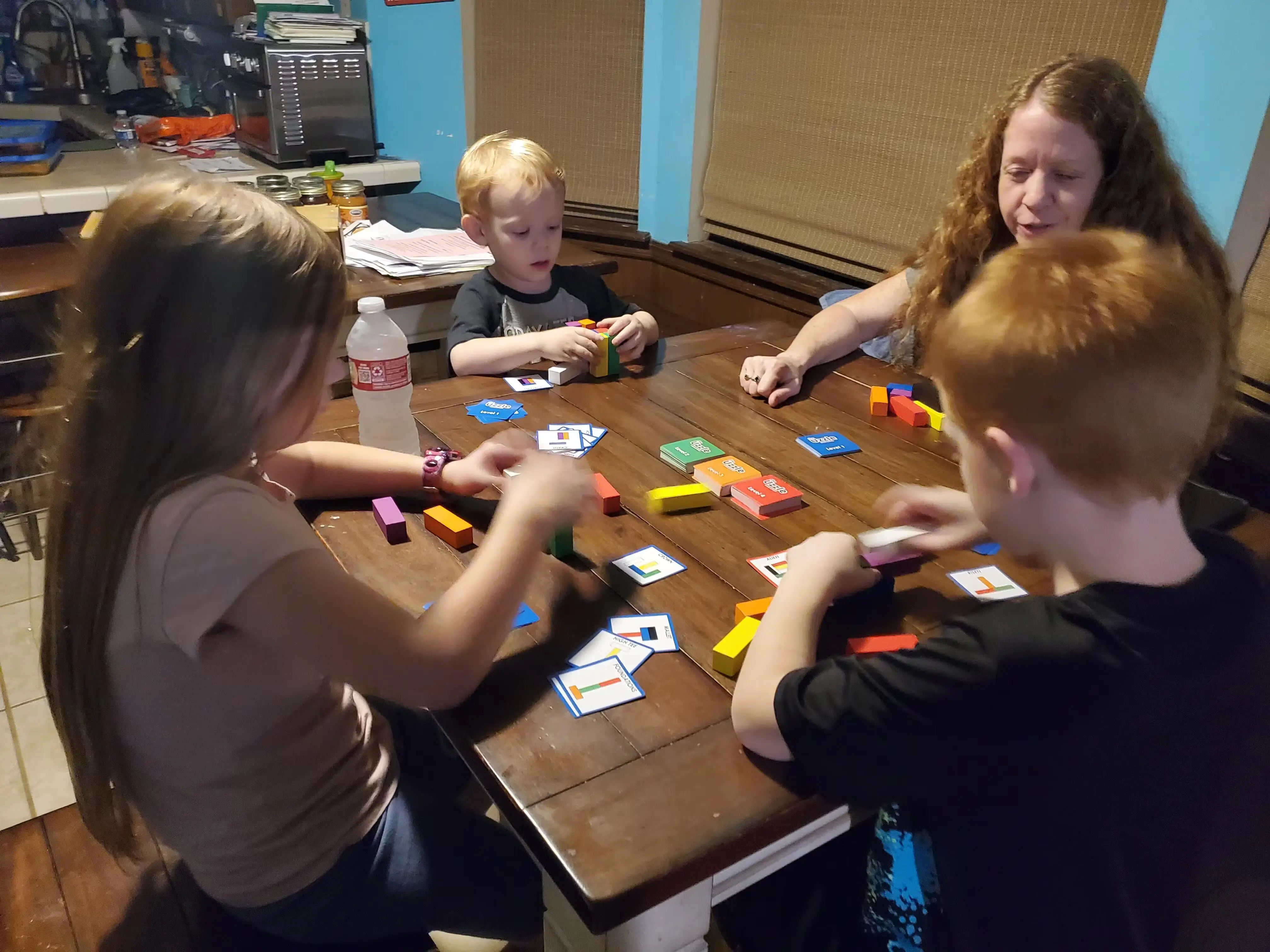 Group playing a colorful block game at a wooden table.