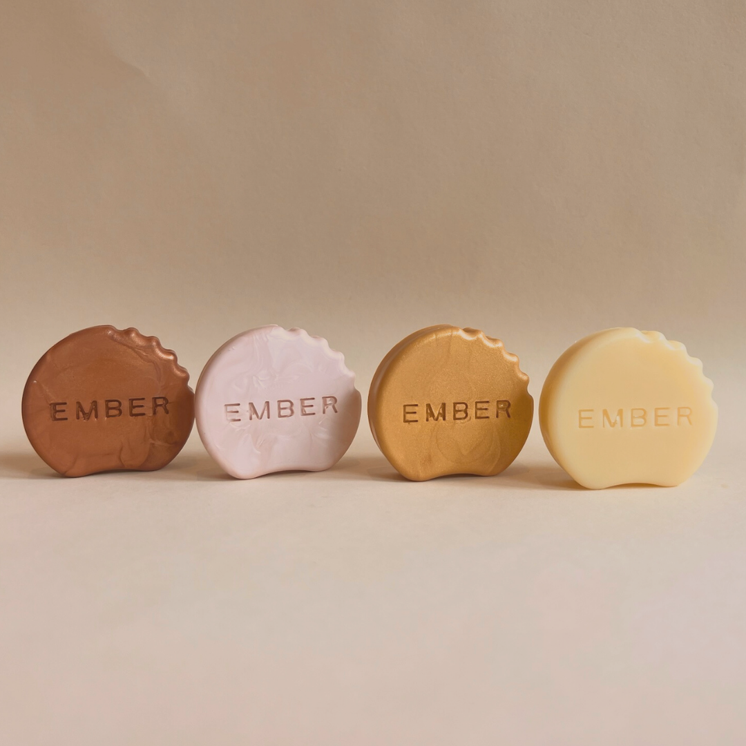 Four round, embossed soaps in different colors on a neutral background.