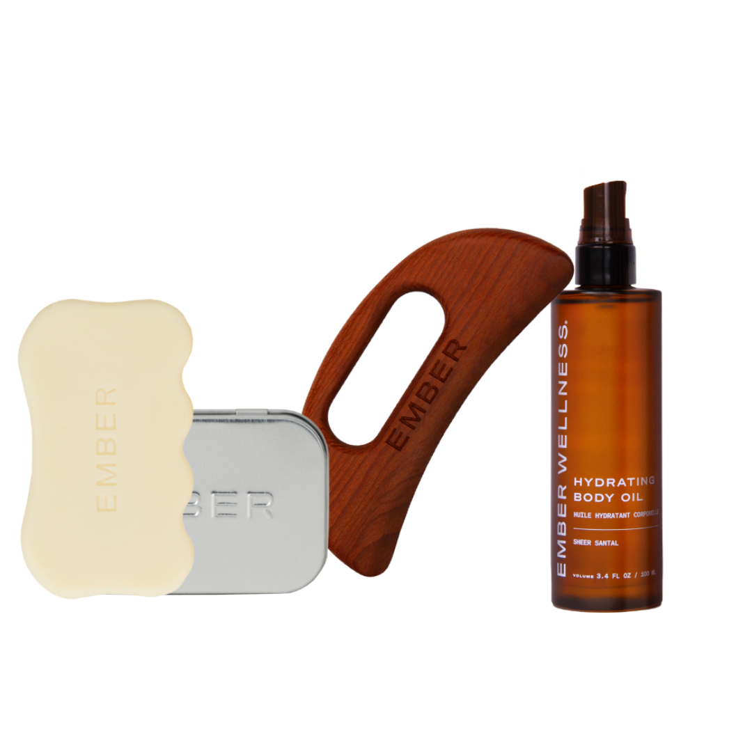 A set of Ember Wellness products including body oil, two gua sha tools, and a metal case.