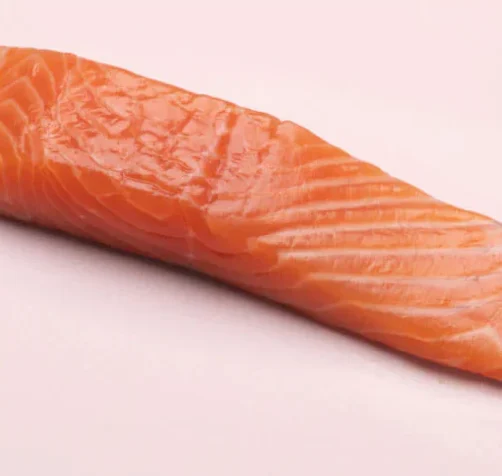 Raw salmon fillet on a light pink background.