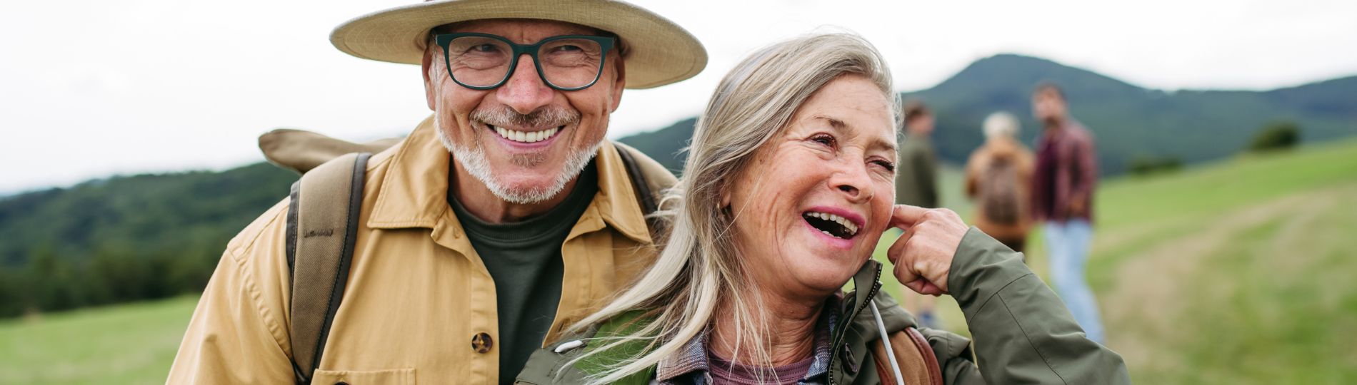 Smiling couple outdoors with mountains in the background.