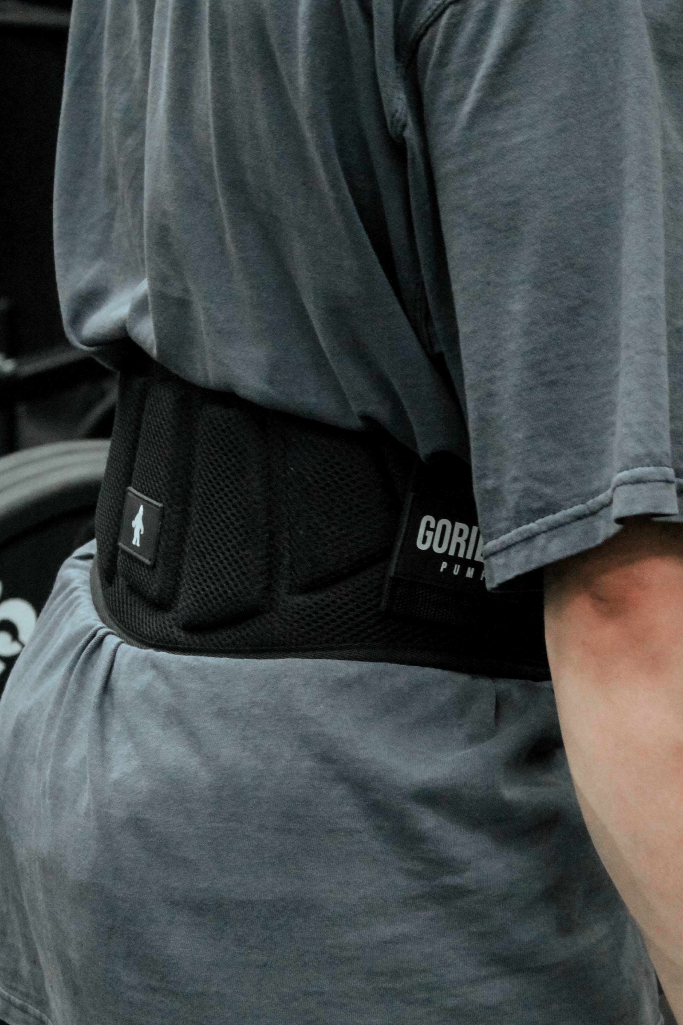 A person viewed from behind wearing a grey t-shirt and a black weightlifting belt.