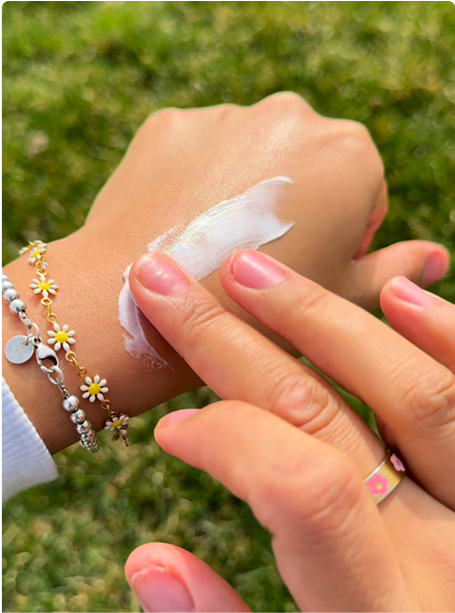 A person's hand applying cream on another hand with bracelets.