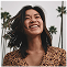 Smiling person outdoors with palm trees in the background.