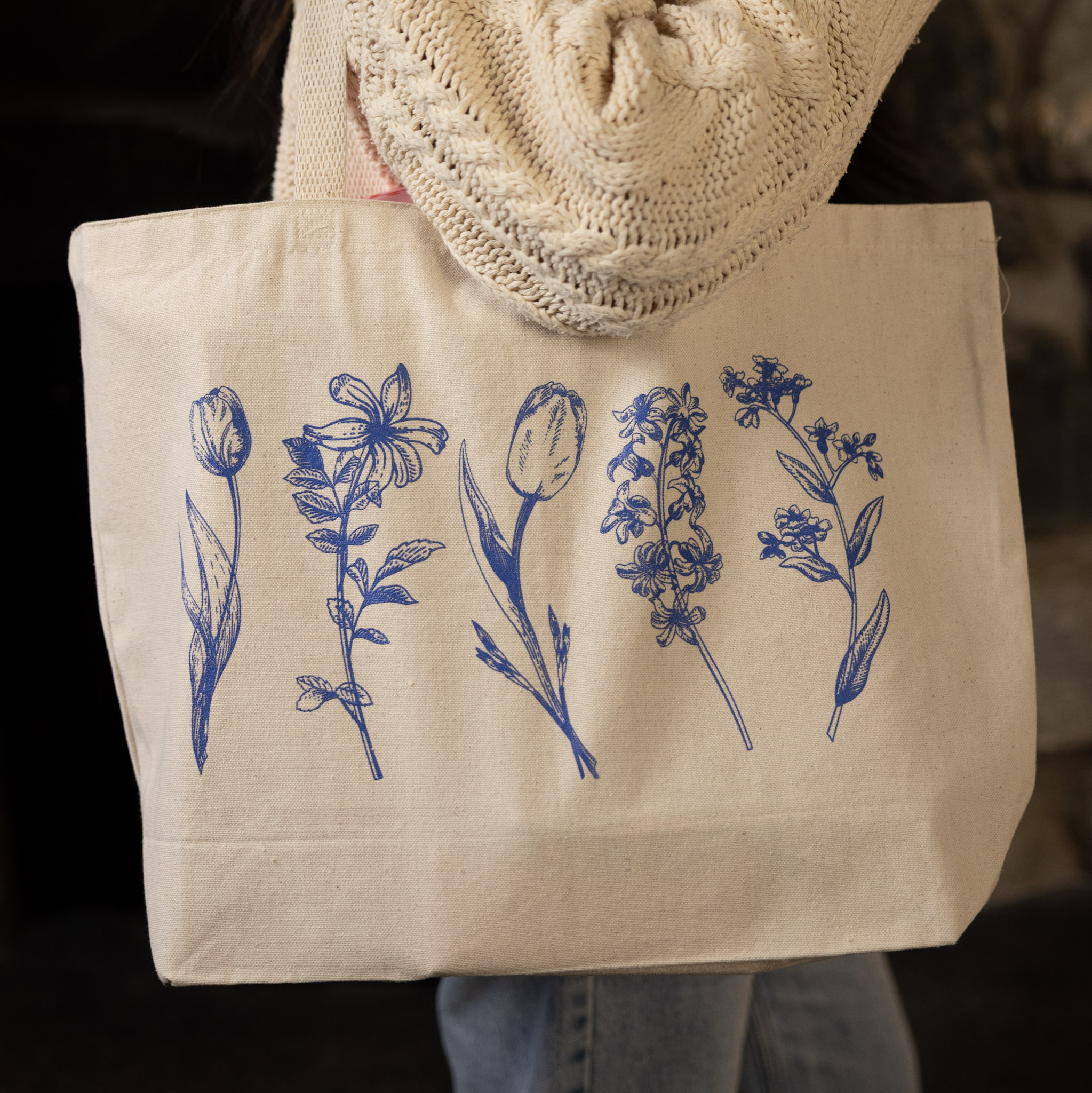 Beige tote bag with blue floral illustrations.