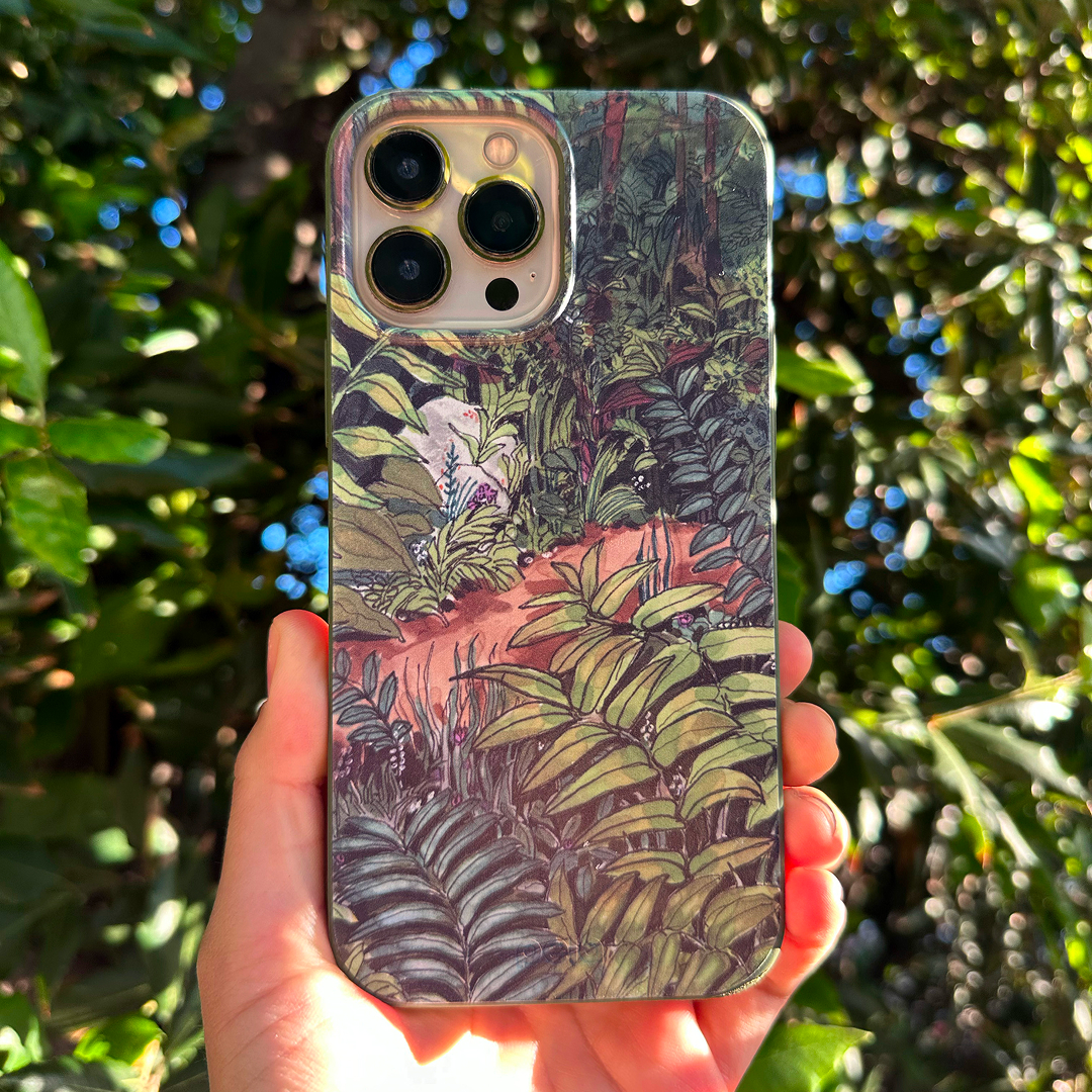 A person's hand holds a smartphone in a case decorated with a lush, illustrated jungle scene.