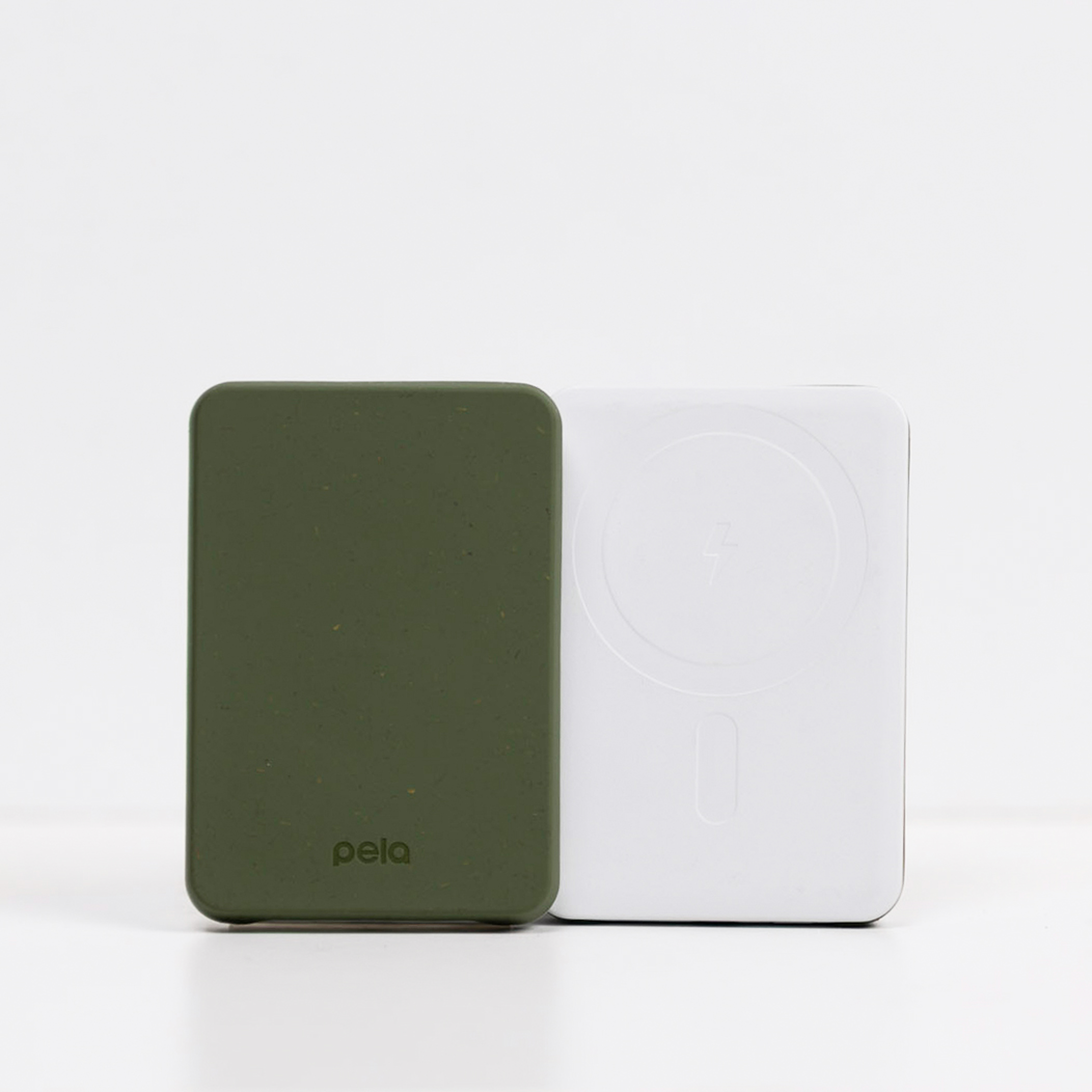An olive green Pela portable charger and a white portable charger stand side-by-side on a white surface.