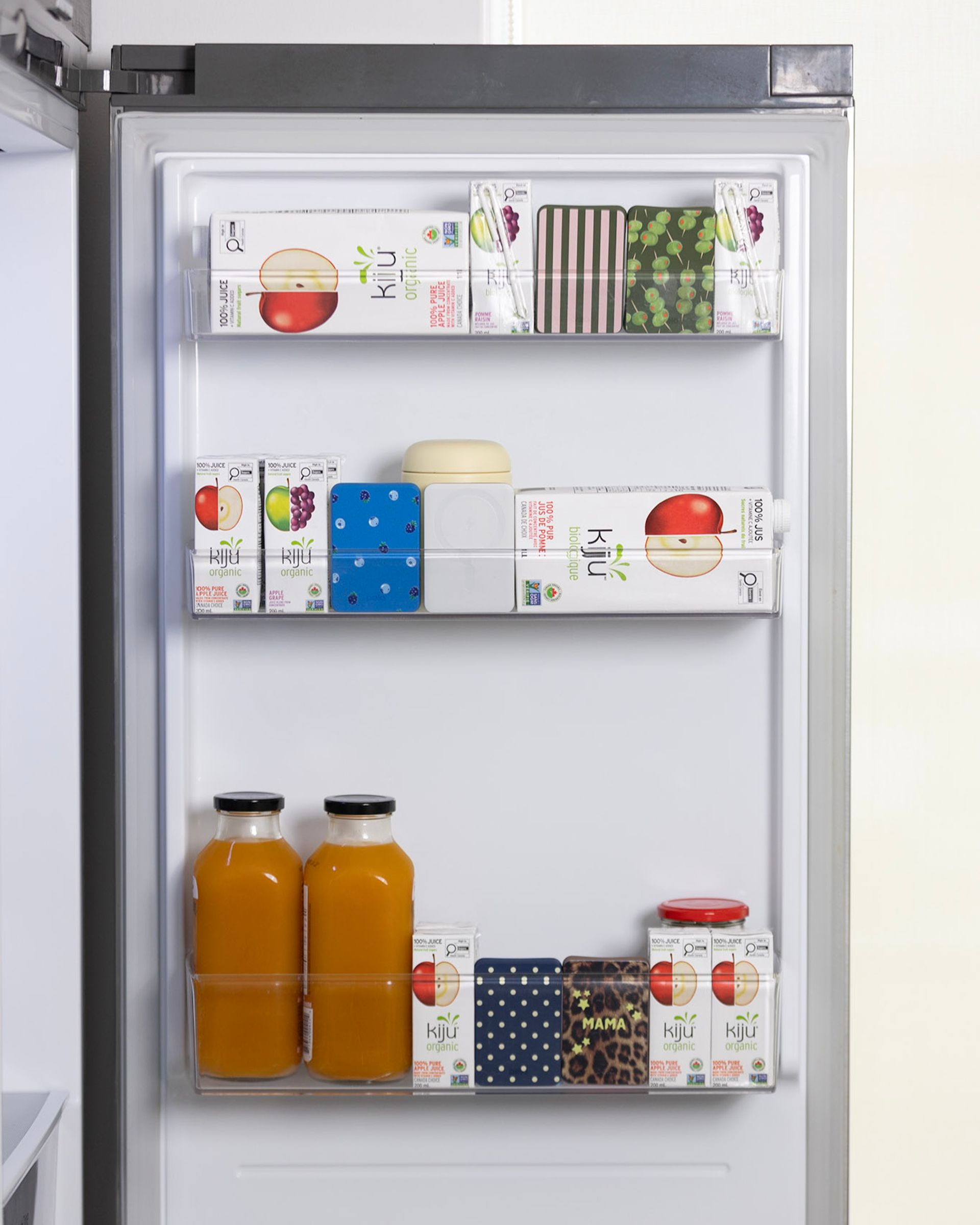 The inside of a refrigerator door with shelves filled with juice boxes, bottles, and other containers.