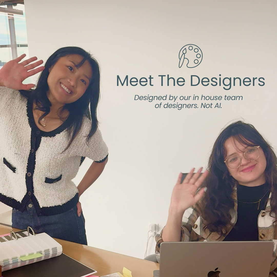 Two women designers smiling and waving at the camera in an office setting.