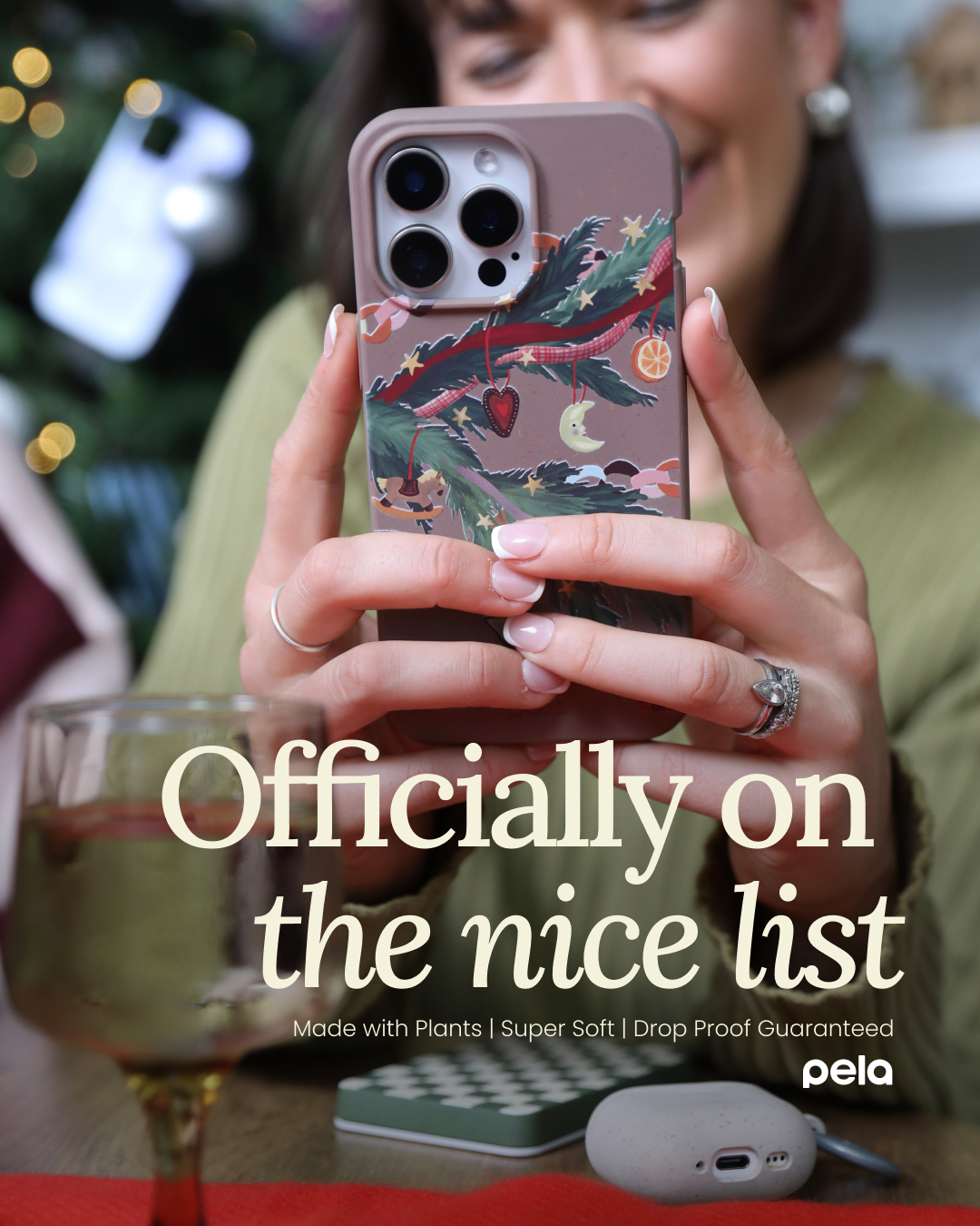 A person holding a smartphone with a Christmas-themed case in front of a festive background.