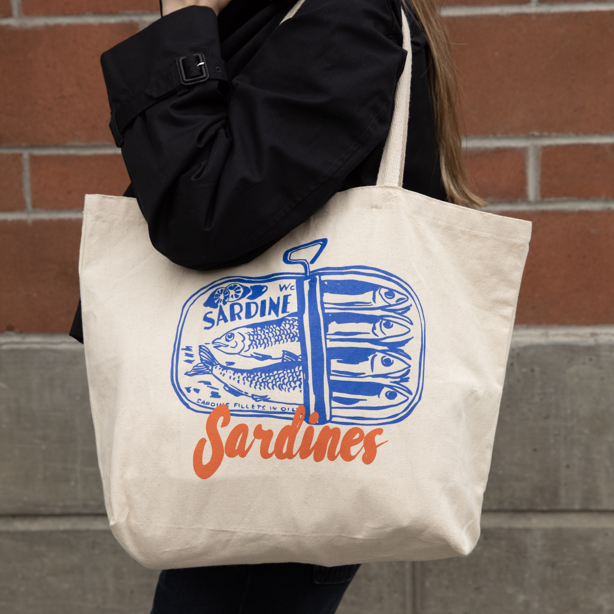 Canvas tote bag with sardine can illustration.