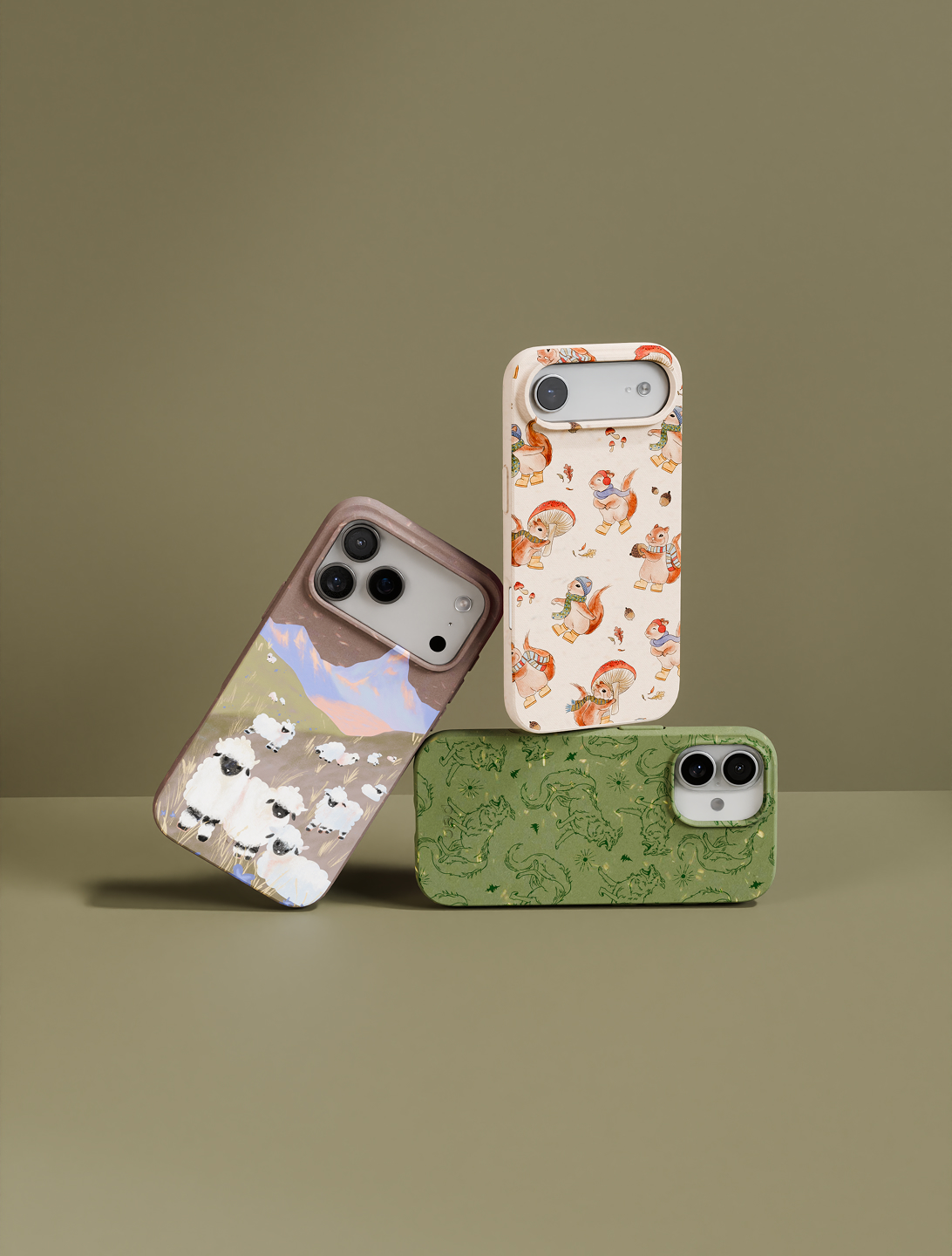 Three illustrated phone cases with animal and nature designs are stacked against a solid green background.