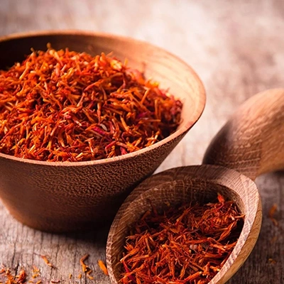 Two wooden bowls filled with saffron threads on a wooden surface.
