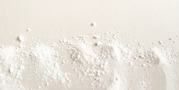 A close-up, top-down view of a fine white powder scattered across a light-colored surface.
