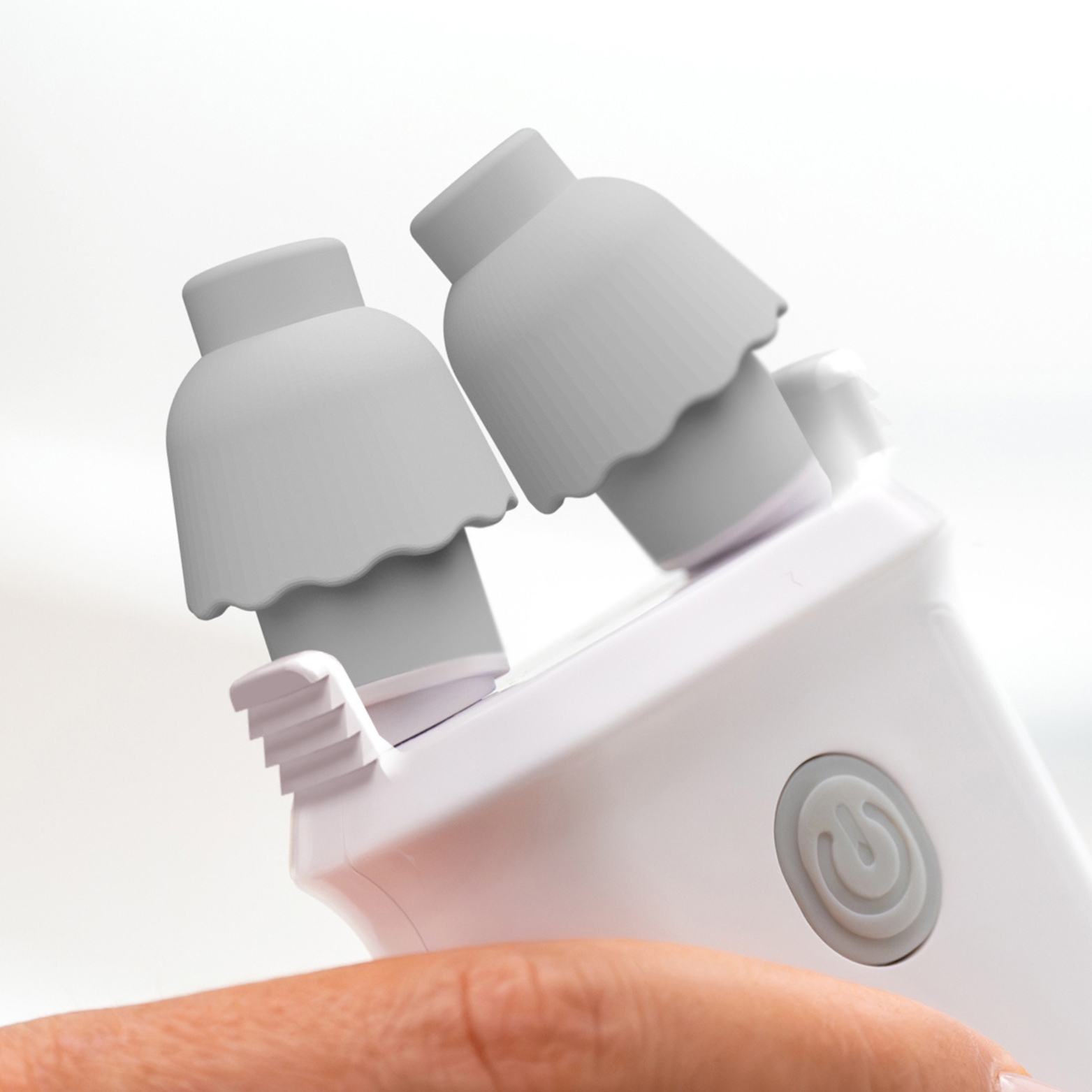 Close-up of a handheld massager with two silicone attachments and a power button.