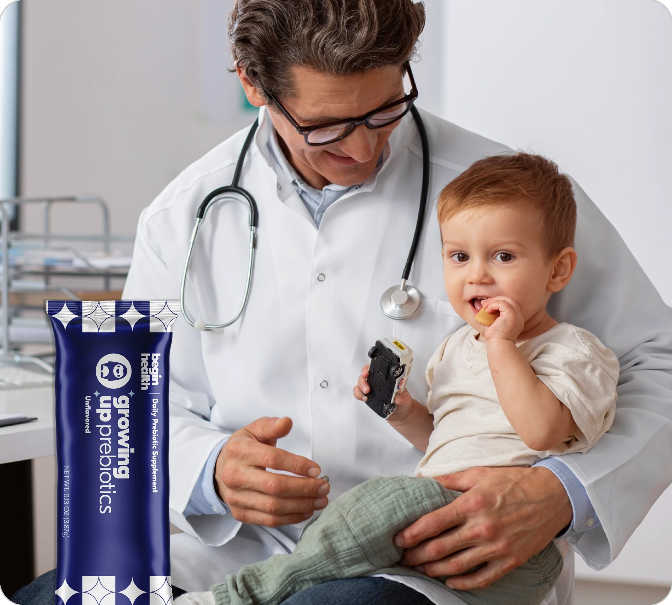 Doctor holding a child eating a snack, with a prebiotics package visible.
