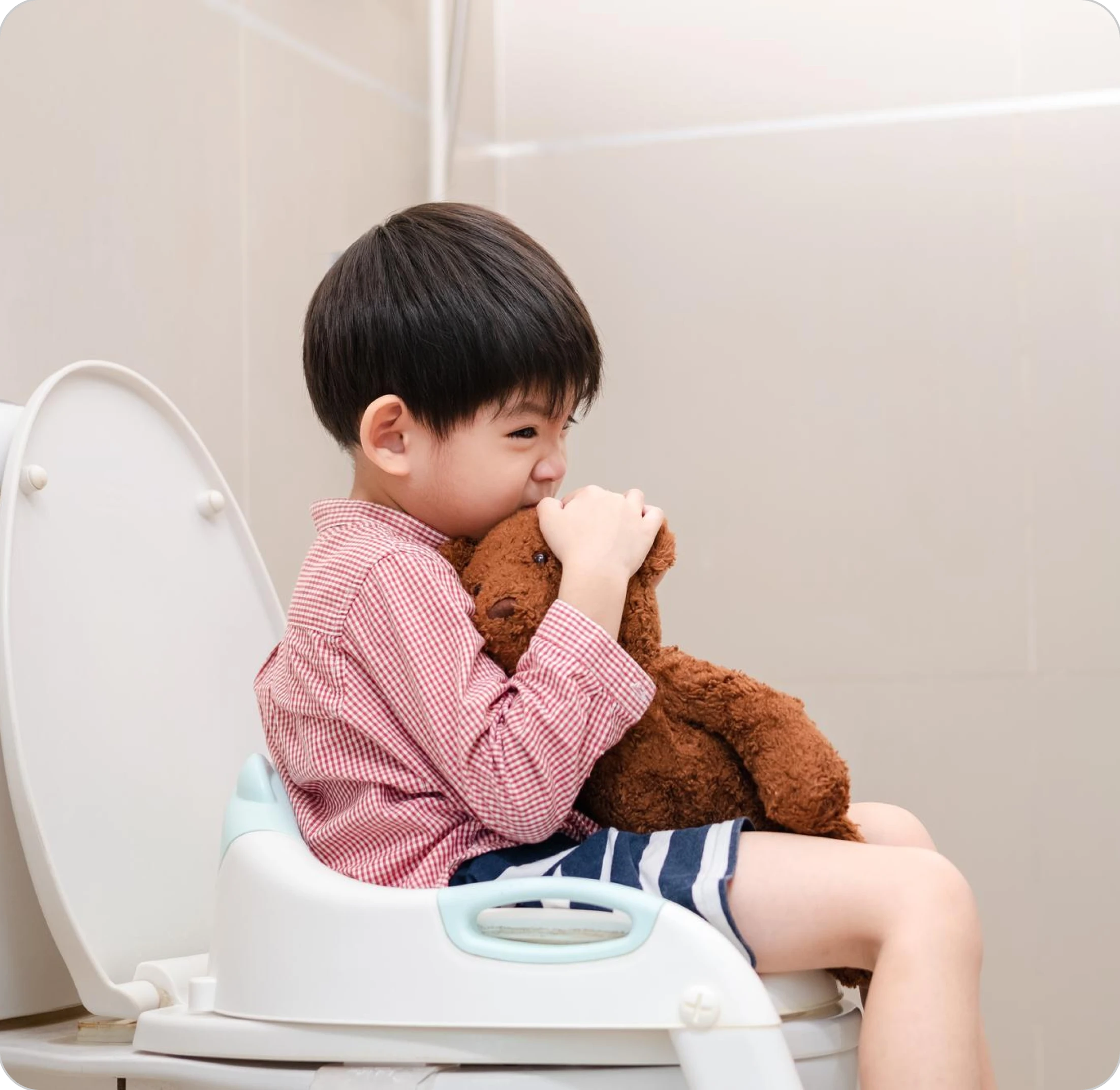 Child sitting on a potty chair, hugging a teddy bear.