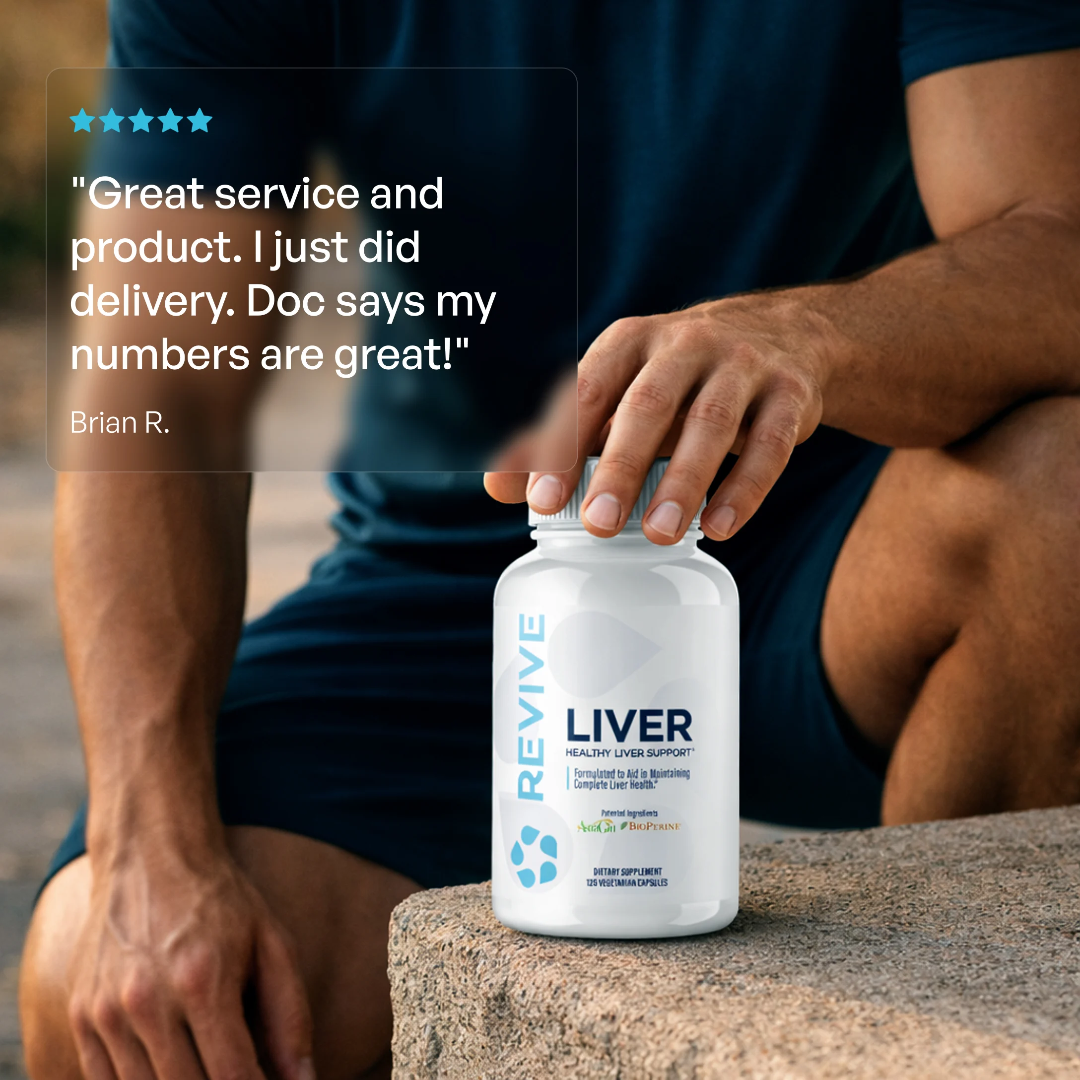 A man in a blue shirt holds a bottle of Revive Liver Support supplements outdoors.