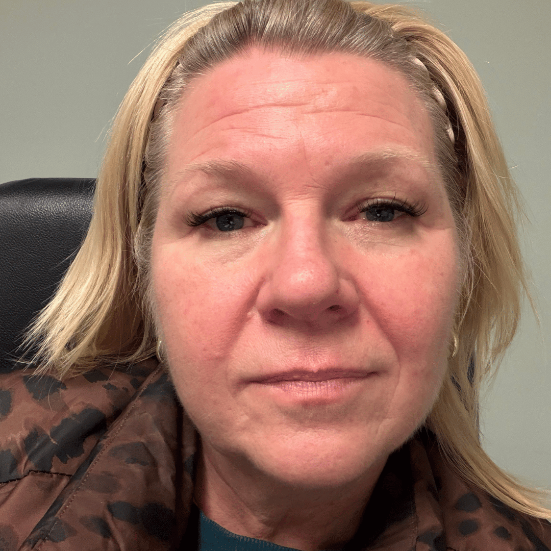 A close-up of a blonde woman with a headband and a patterned jacket looking at the camera.