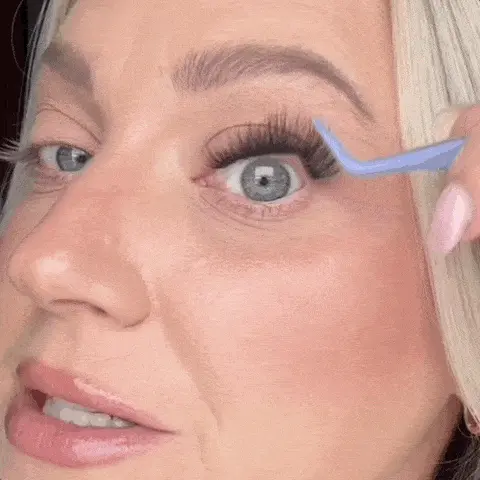 A close-up of a woman using a blue tool to apply false eyelashes to her upper eyelid.