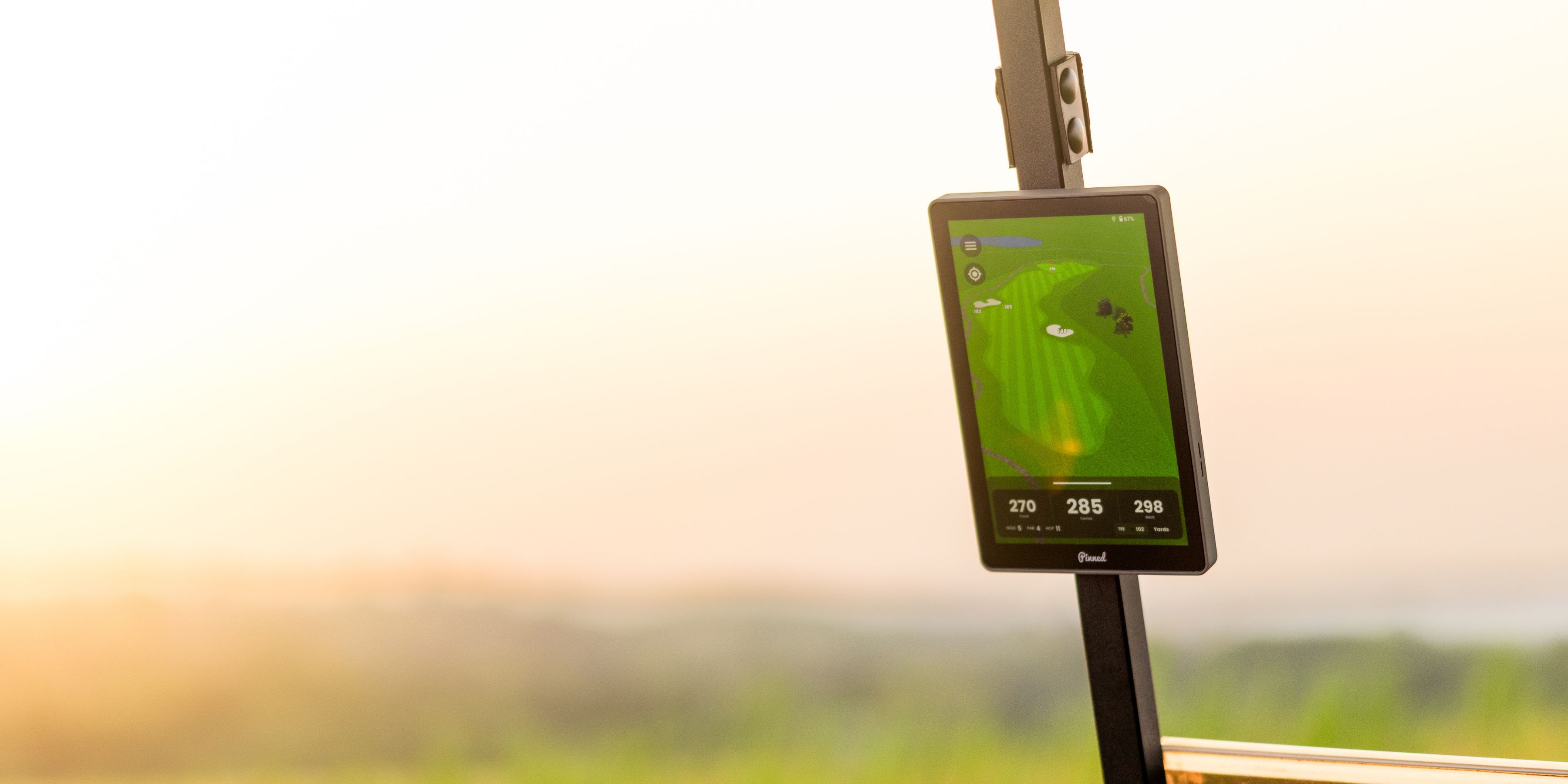 A close-up of a golf cart GPS screen displaying a course map with a hazy, warm background.