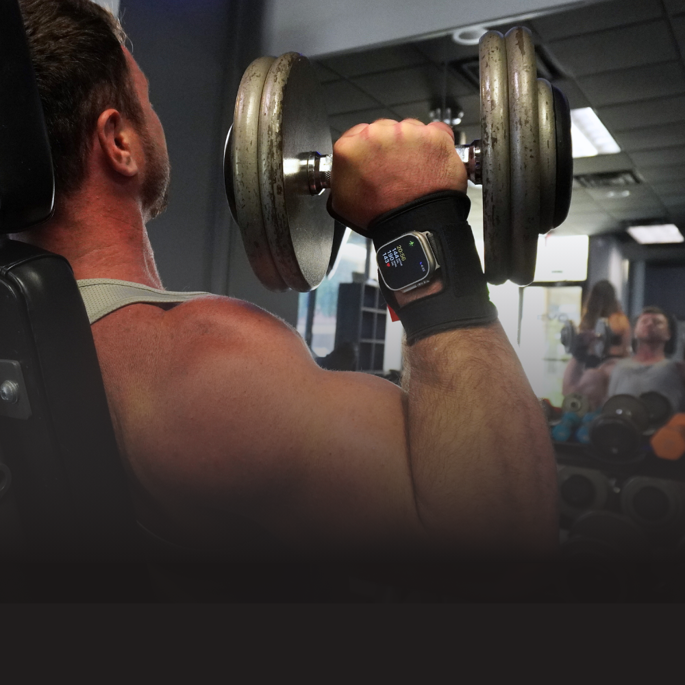 Man lifting dumbbells in a gym, wearing a smartwatch.