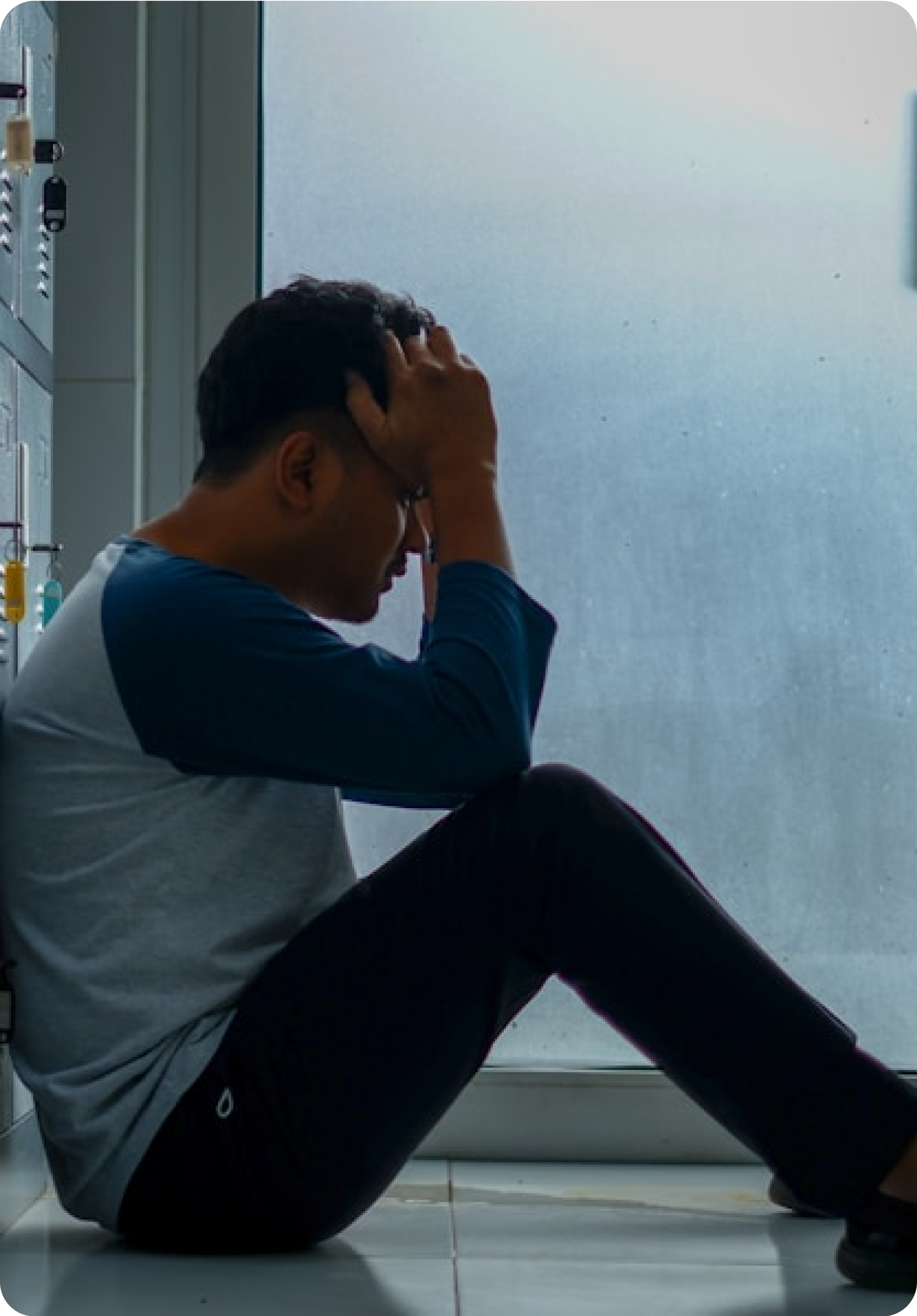 Person sitting on the floor, holding their head in distress.