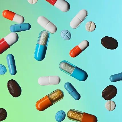 Various colorful pills and capsules on a gradient background.