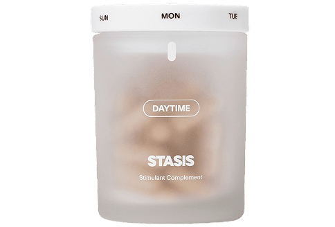 Frosted jar labeled 'STASIS Daytime Stimulant Complement' with white lid showing days of the week.
