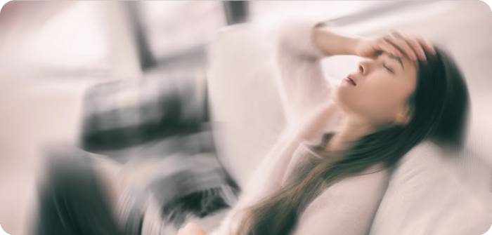 Blurred image of a person sitting with hand on forehead, appearing distressed.