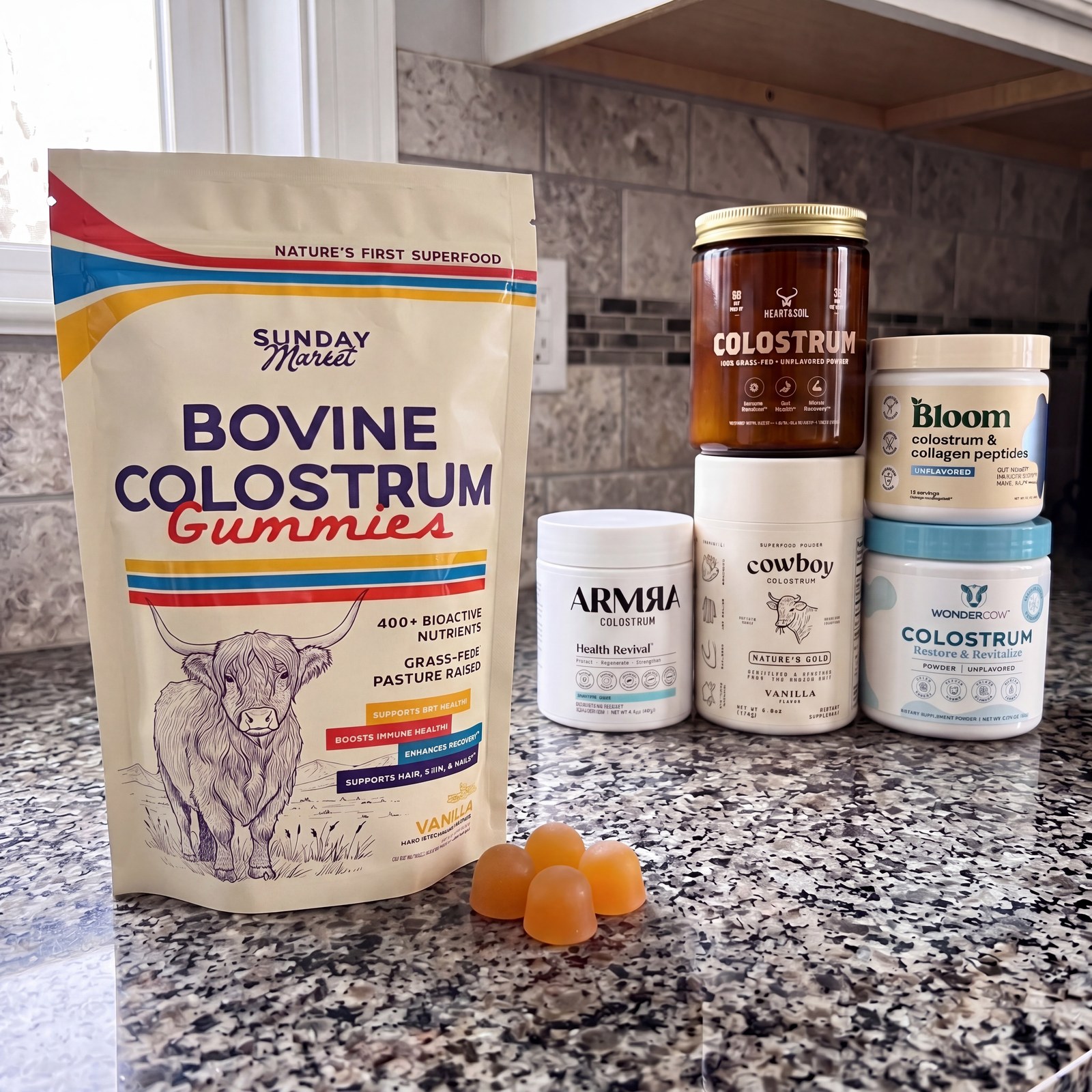 An assortment of bovine colostrum health supplements in gummy and powder form on a counter.