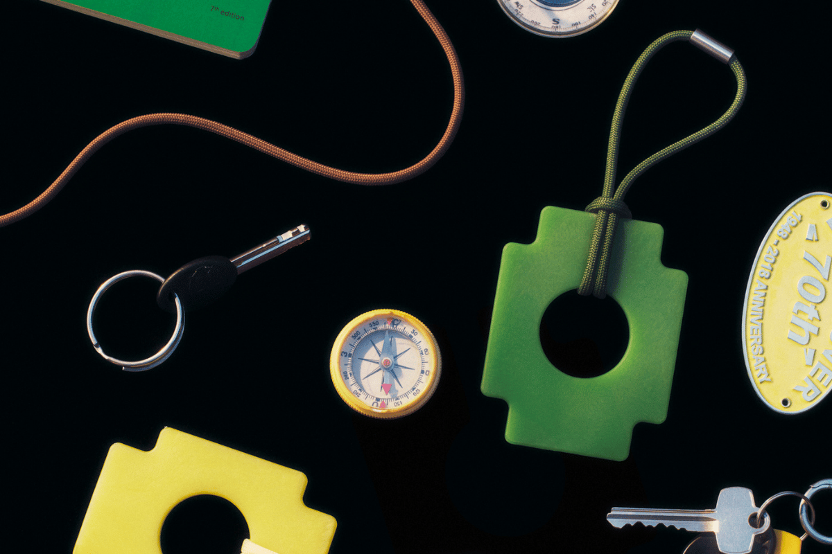 A variety of outdoor tools including a compass, keys, and tags on a black background.