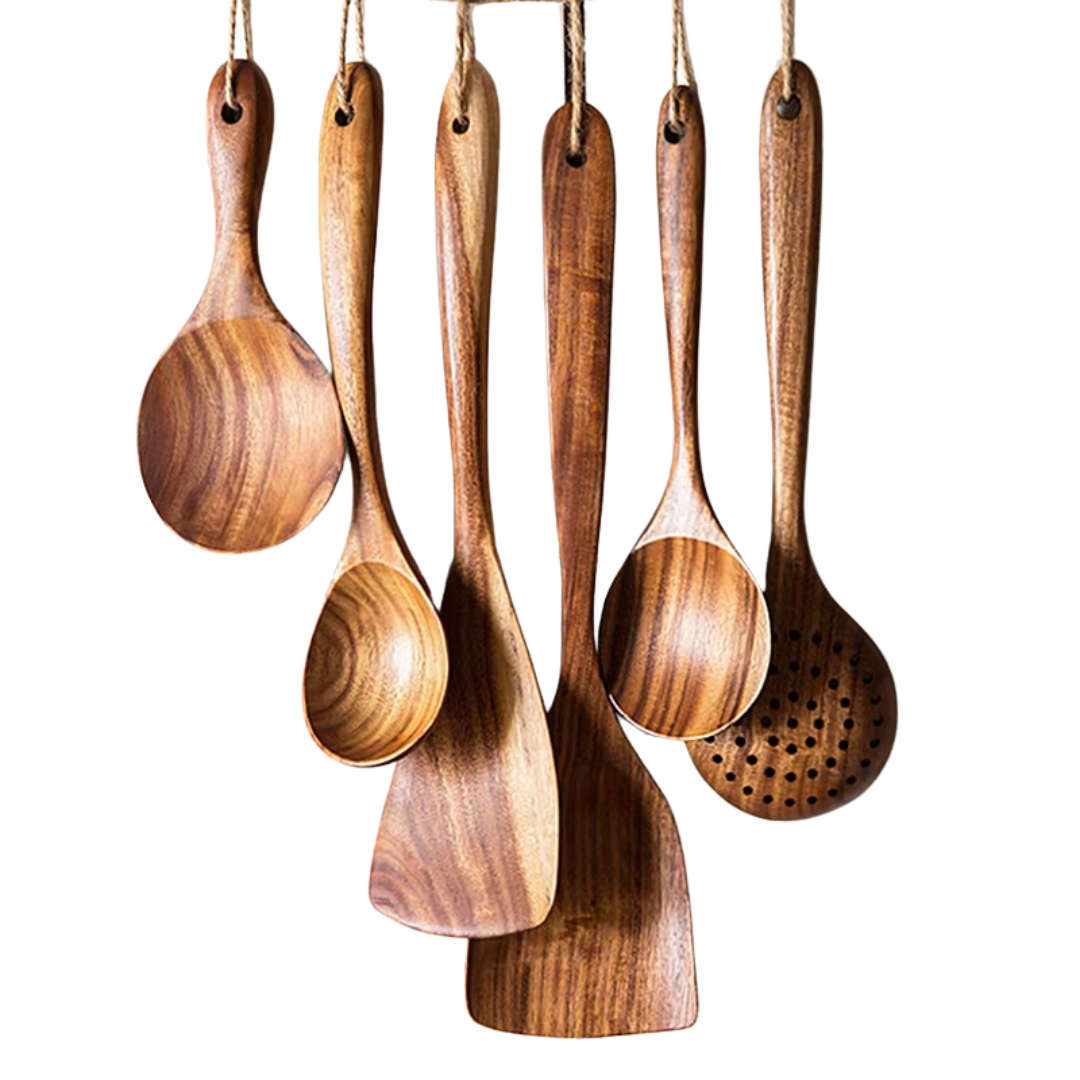 Wooden cooking utensils hanging against a white background.