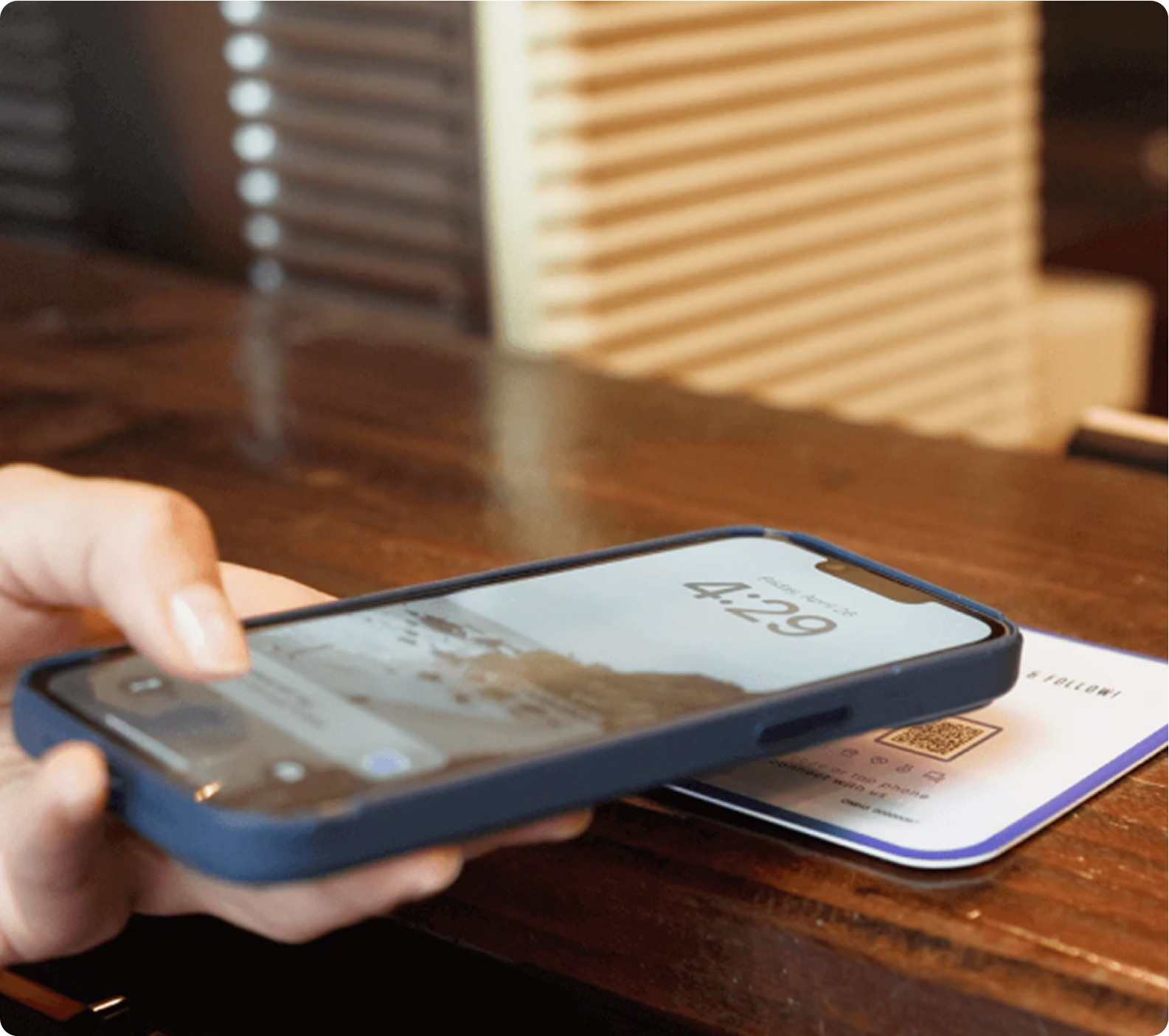 Hand holding phone over a QR code on a table.