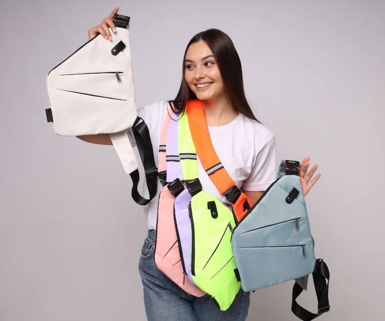 Person holding multiple colored crossbody bags.