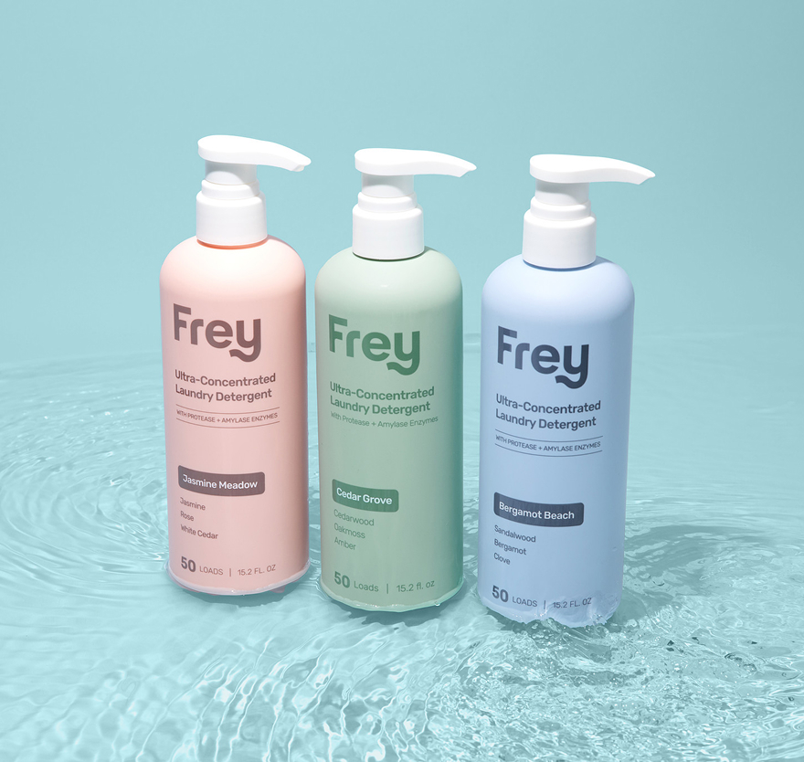 Three bottles of Frey laundry detergent on a watery surface.