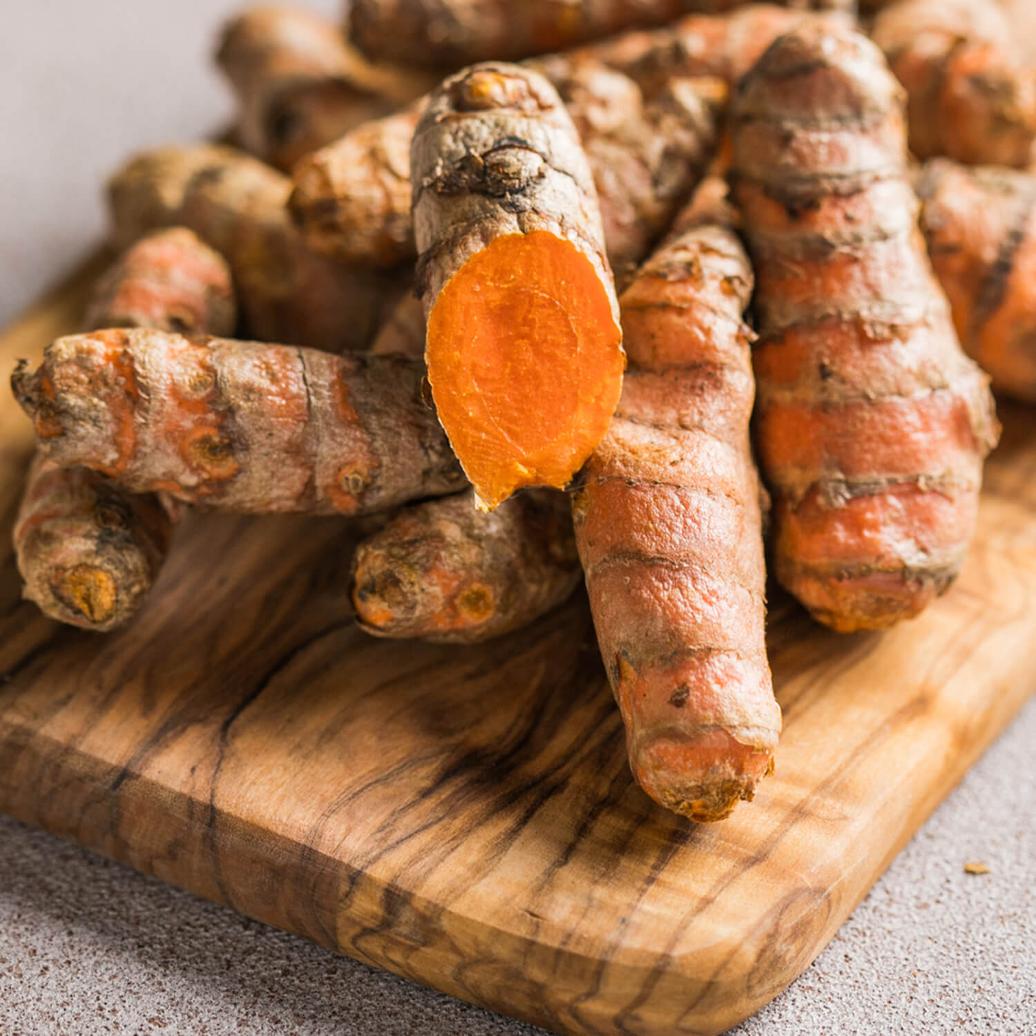 Fresh turmeric roots on a wooden cutting board.