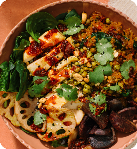 Colorful salad bowl with greens, grilled tofu, nuts, and lotus root slices.