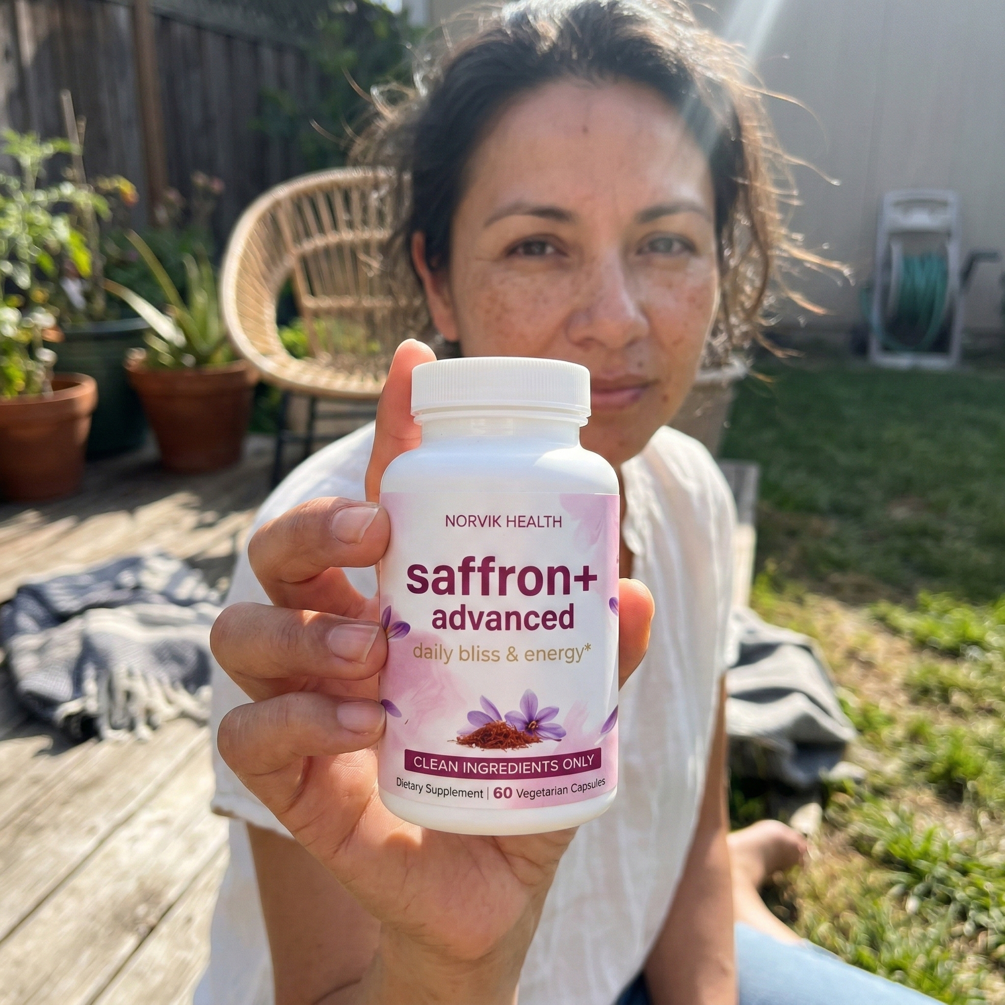 An older man with white hair smiles while holding a bottle of Saffron+ Vision supplements.