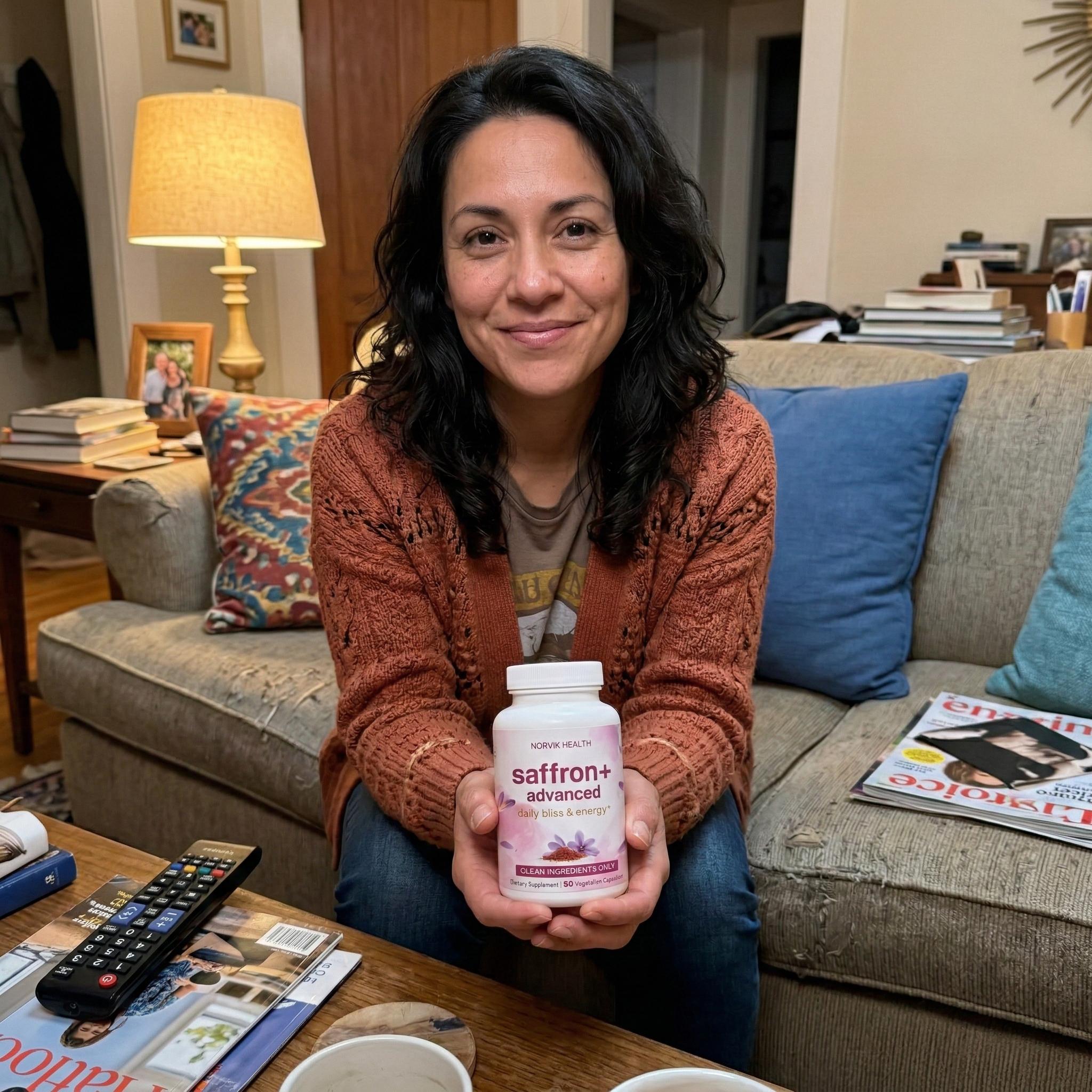 A smiling woman sits on a couch, holding up a white bottle of saffron supplements.