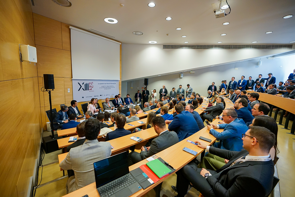 A wide shot of a crowded lecture hall during a conference panel discussion.
