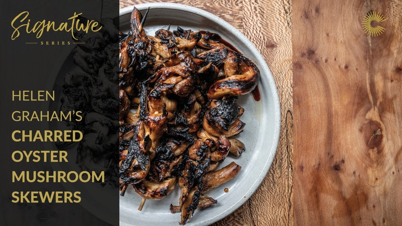 Plate of charred mushroom skewers on a wooden table.
