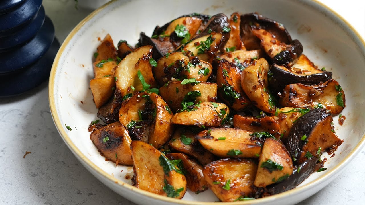 Sautéed mushrooms and herbs in a white bowl on a table.