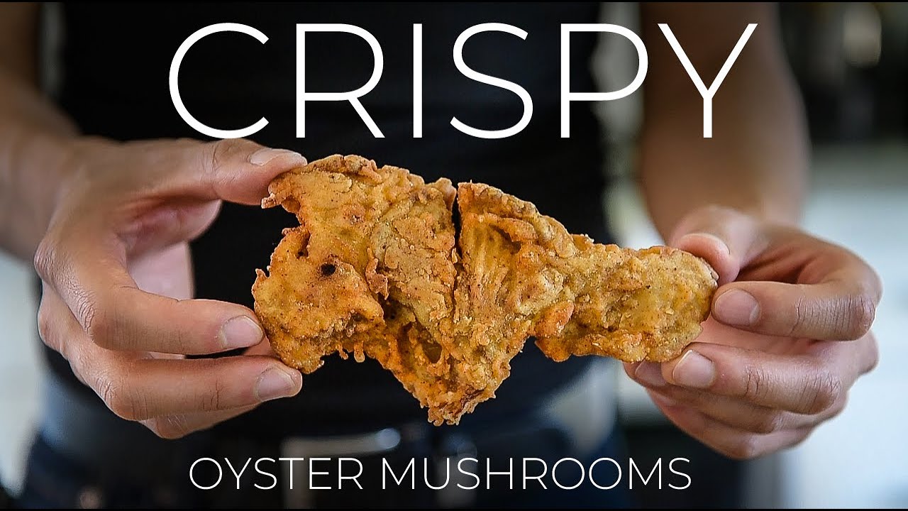 Person holding fried oyster mushroom, text reads 'CRISPY OYSTER MUSHROOMS'.