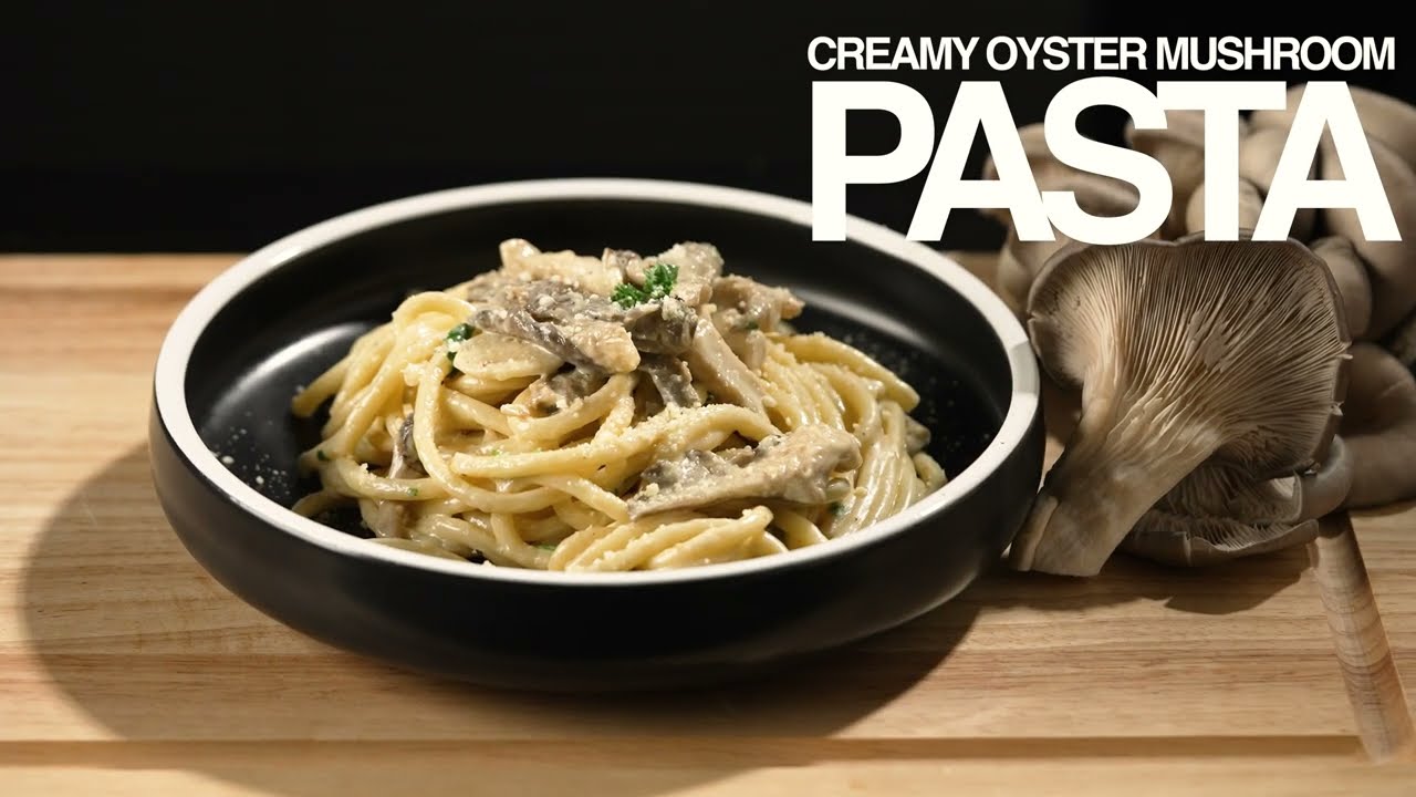 Plate of creamy oyster mushroom pasta with whole mushrooms beside it.