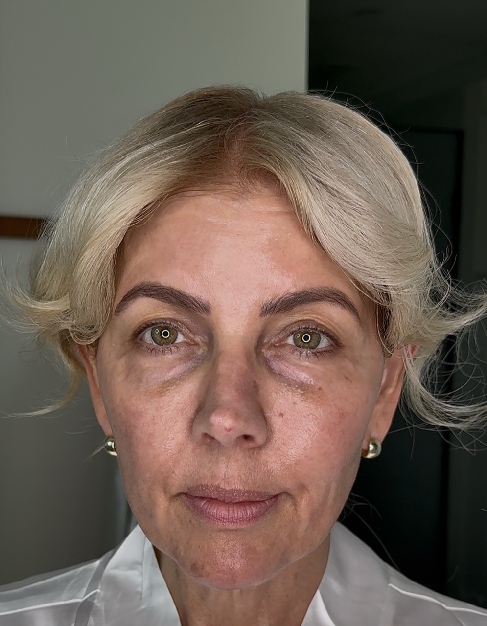 A close-up, front-facing photo of a woman with short blonde hair and green eyes.