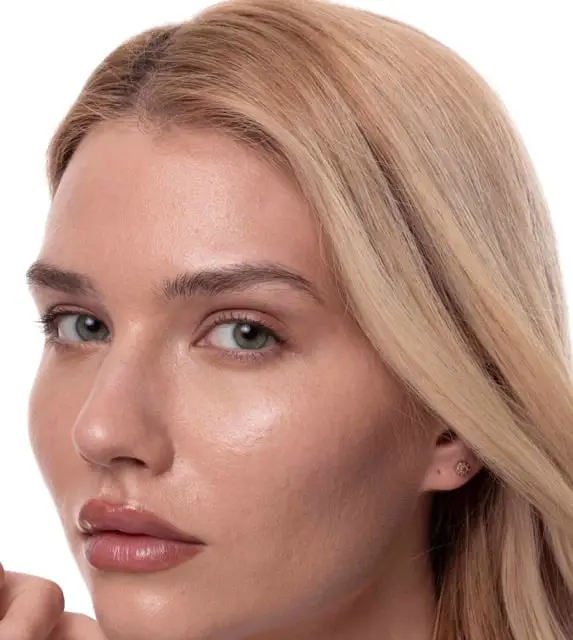 A close-up portrait of a woman with blonde hair and green eyes against a white background.